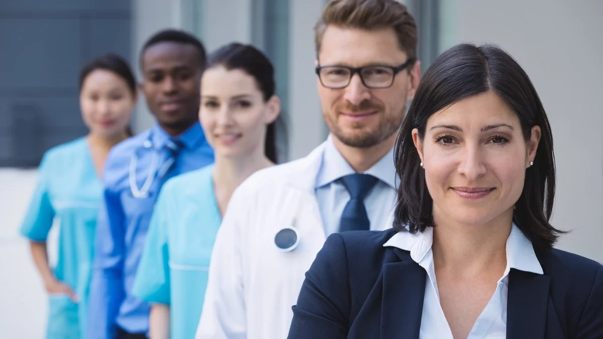 A team of doctors and nurses stand in a row with a healthcare executive representing a Fractional CMO. 